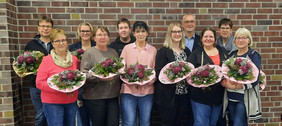 Geehrte Mitarbeiterinnen und Mitarbeiten mit Blumensträußen