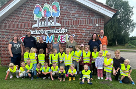 Die Kita-Kinder tragen gelbe Warnwesten und haben sich zu einem Gruppenfoto mit den Leiterinnen und den Spendern aufgestellt.