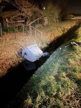 Ein Abfallcontainer liegt in einem Graben