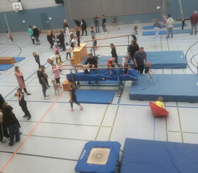 Kinder turnen in einer Sporthalle an Turngeräten