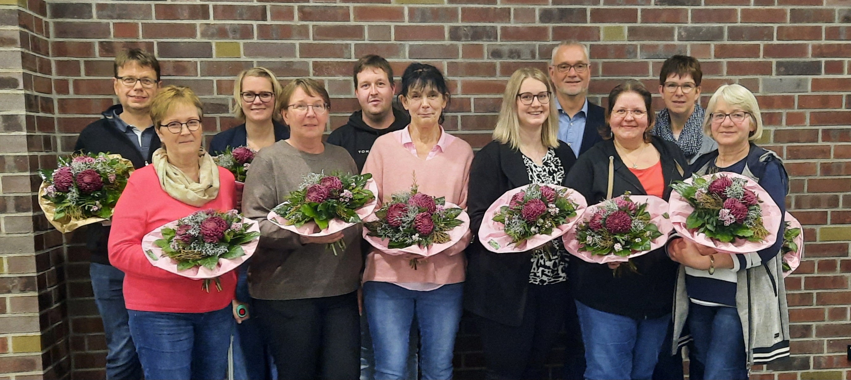 Geehrte Mitarbeiterinnen und Mitarbeiten mit Blumensträußen