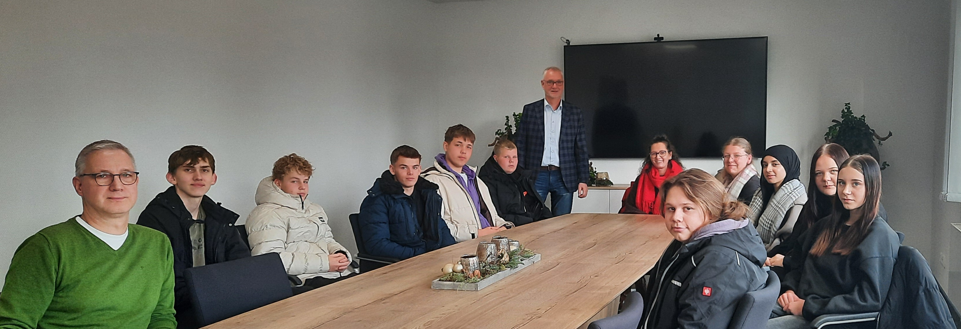 Die Schülerinnen und Schüler sitzen mit dem Bürgermeister, der Lehrerin und dem Fachbereichsleiter an einem Tisch.