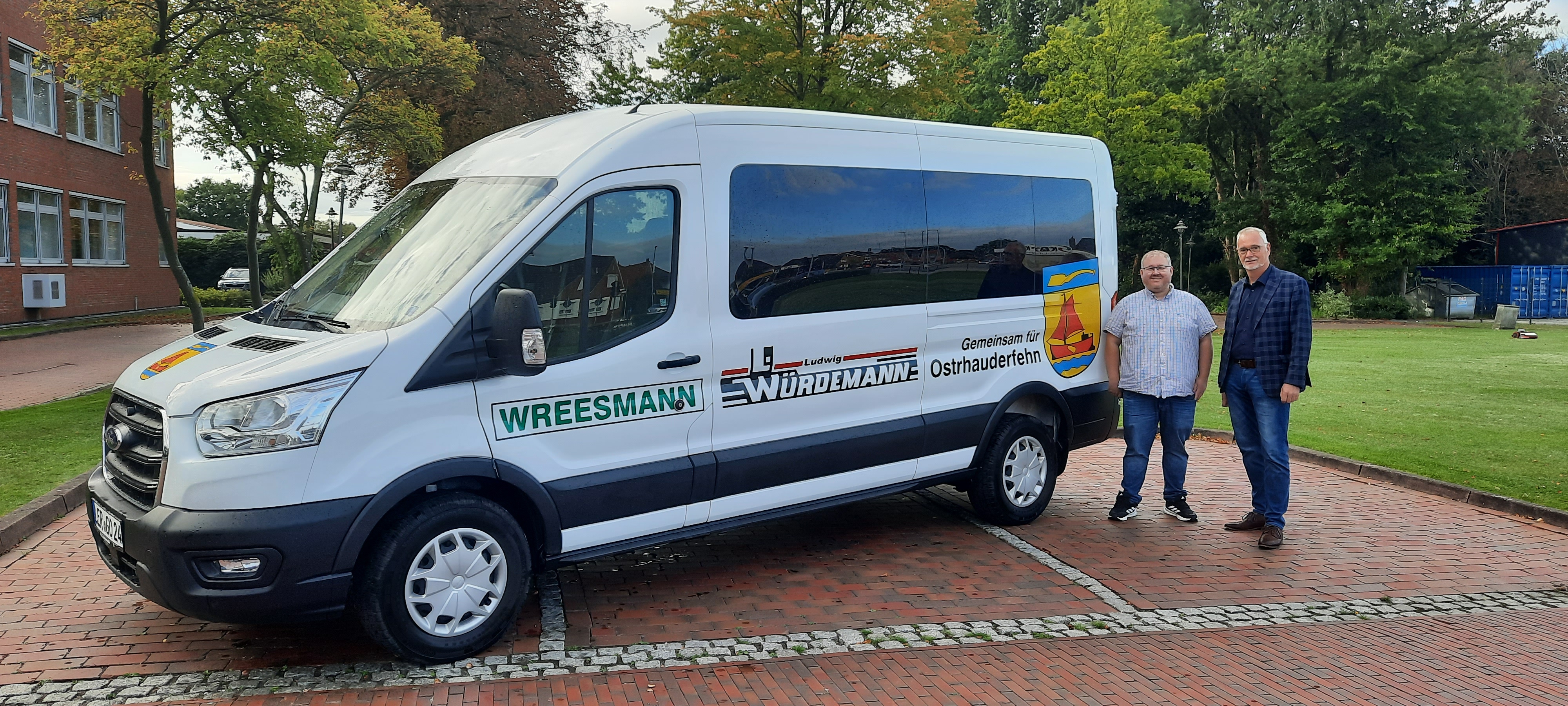 Hinten rechts neben einem weißem Ford Transit Transporter stehen Tourist-Mitarbeiter Heiko Tinnemeyer und Bürgermeister Günter Harders
