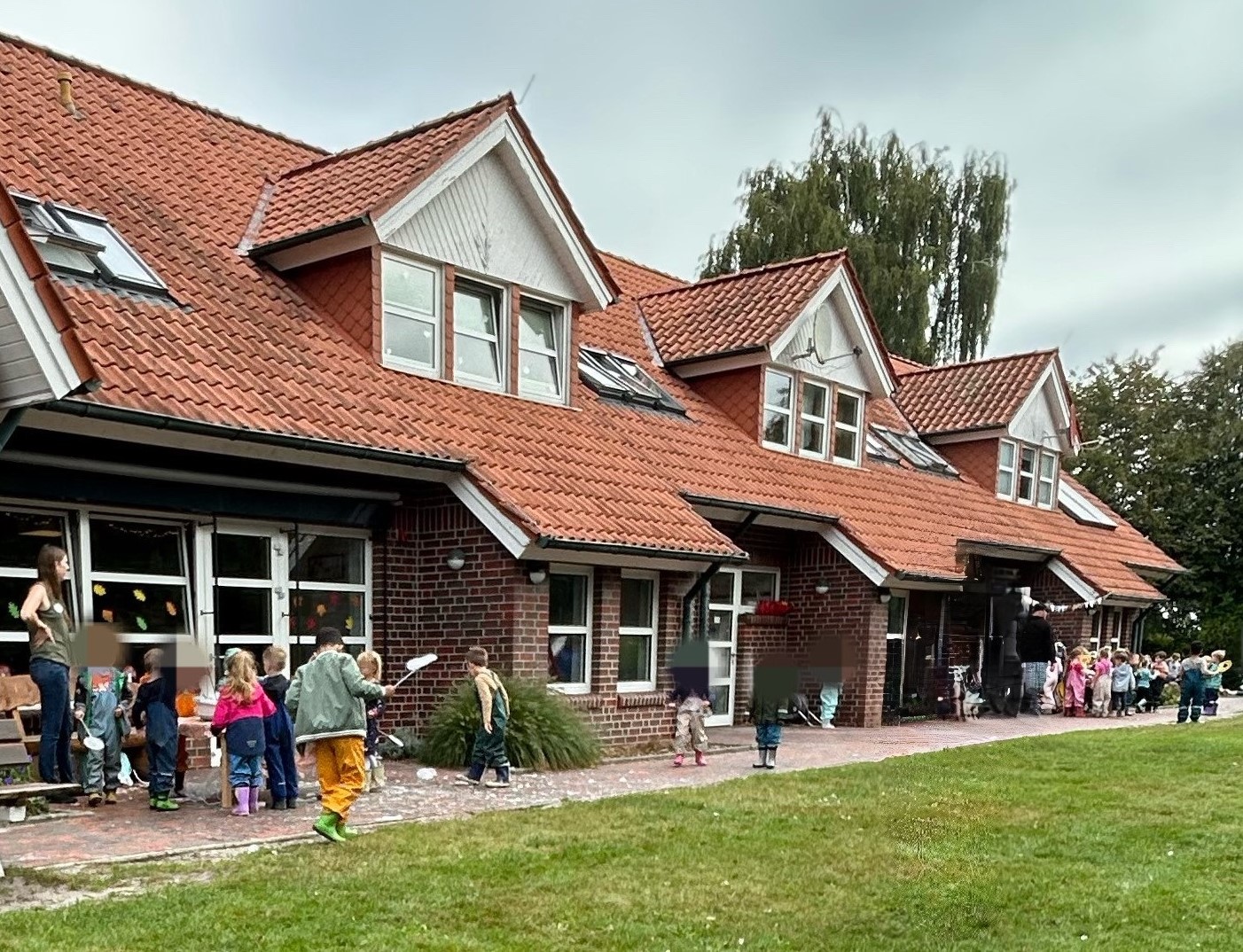 Vor dem Gebäude der Kindertagesstätte Farbenwelt stehen Kinder in zwei Gruppen zusammen