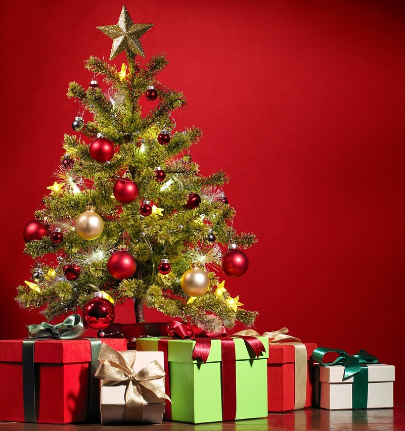 Ein geschmückter Weihnachtsbaum mit Geschenkpaketen vor rotem Hintergrund