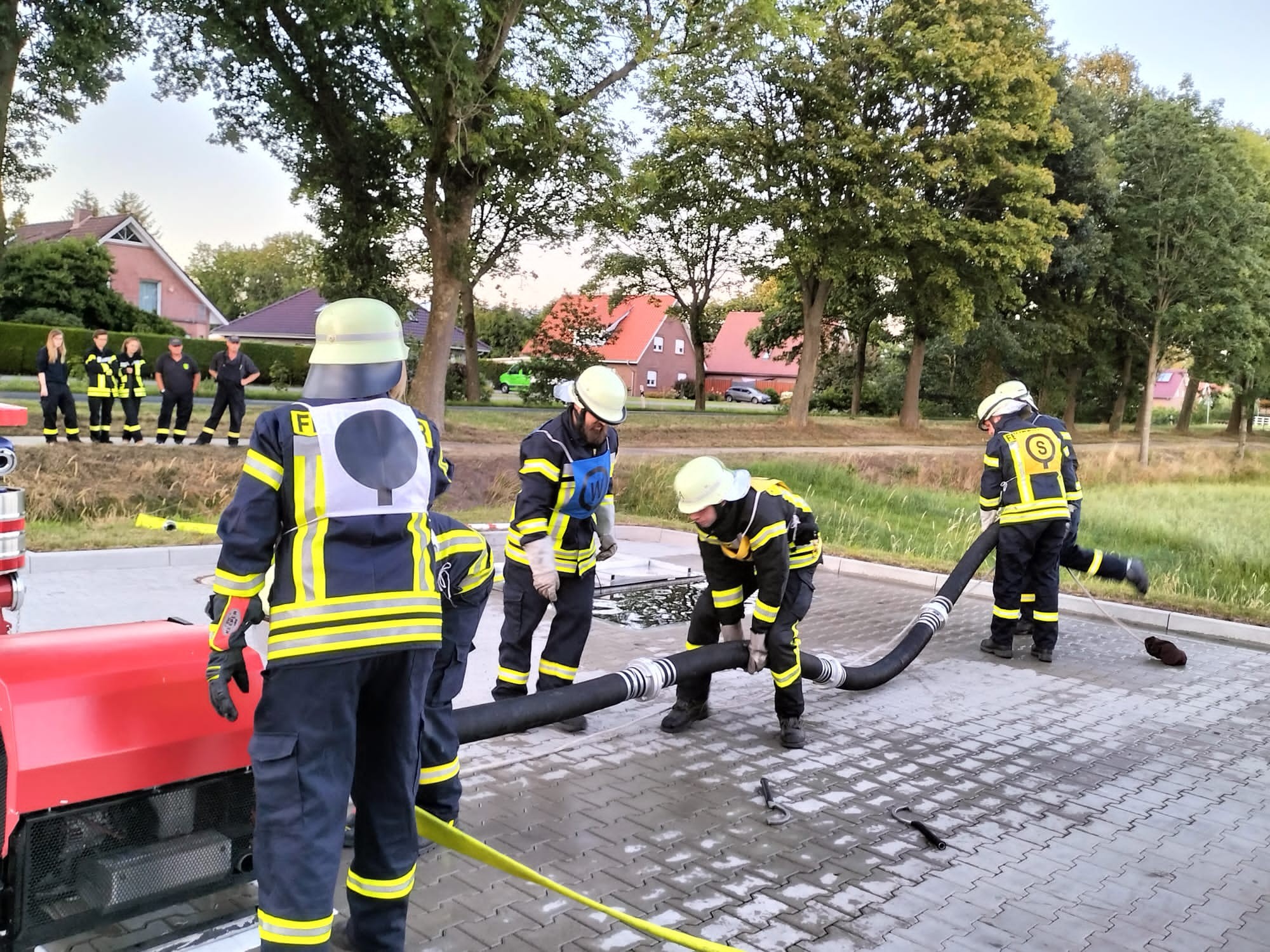 Feuerwehrmänner rollen einen Feuerwehrschlauch aus
